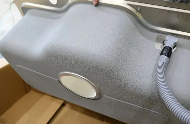 Underside of a kitchen sink with anti-condensation coating and silencer pads.