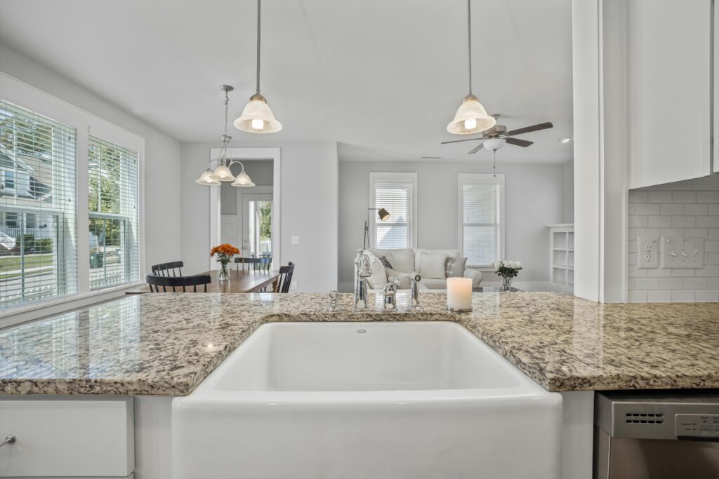 Bright and spacious kitchen interior showcasing granite countertops and a ceramic sink with natural light.
