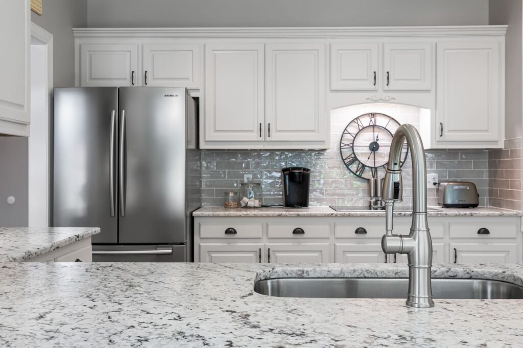 Elegant white kitchen featuring stainless steel appliances, granite countertops, and modern design elements.