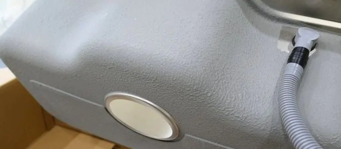 Underside of a kitchen sink with anti-condensation coating and silencer pads.