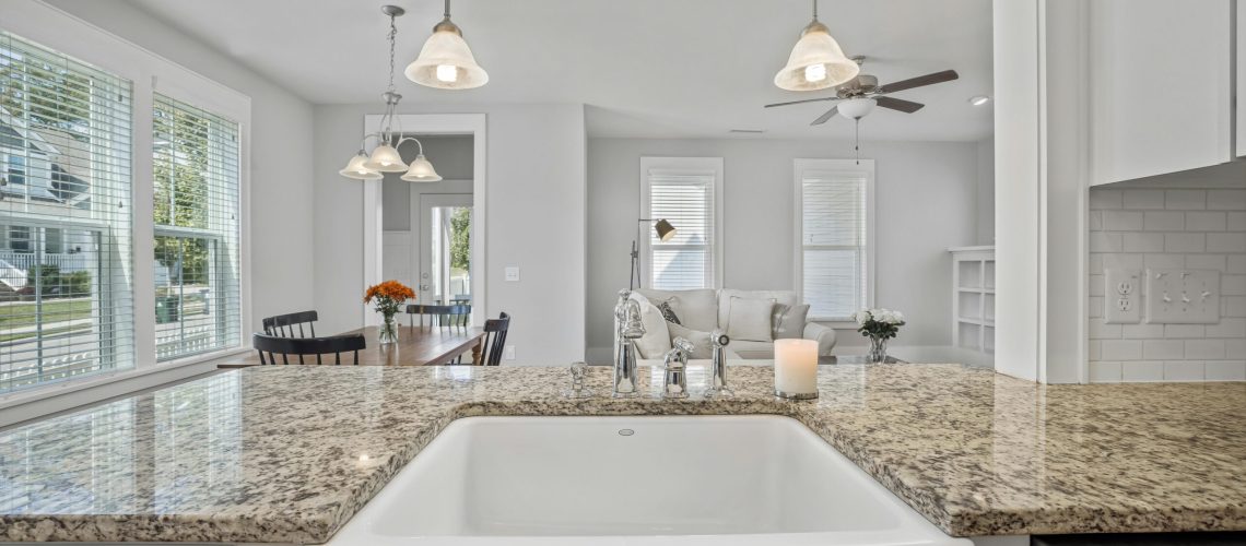 Bright and spacious kitchen interior showcasing granite countertops and a ceramic sink with natural light.
