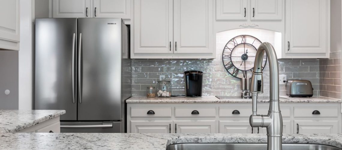 Elegant white kitchen featuring stainless steel appliances, granite countertops, and modern design elements.