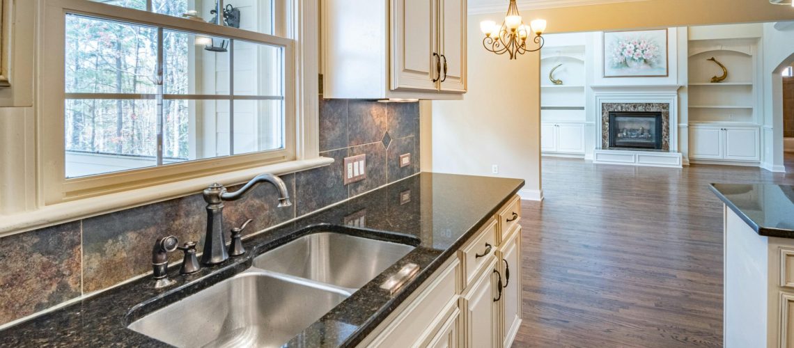 Spacious kitchen with granite countertops, stainless steel sink, and elegant chandelier lighting.